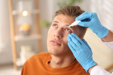 Doktor içerideki adamın gözüne damla damlatıyor, yakın plan. Metin için boşluk