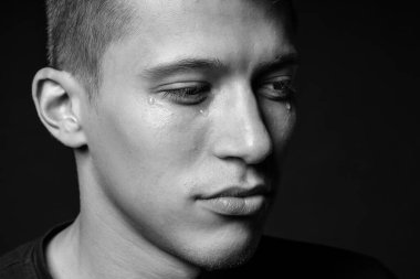 Üzgün adam karanlık arka planda ağlıyor, yakın planda. Siyah ve beyaz etkisi