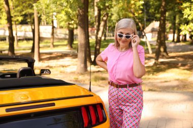 Modern Cabriolet yakınlarında güneş gözlüklü şık bir son sınıf öğrencisi.