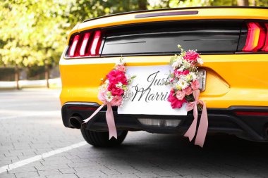 Düğün arabası. Cabriolet dekore edilmiş. Sadece evlilik kartı ve açık havada güzel çiçekler, yakın plan.