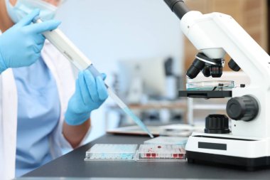 Genetik araştırması. Mikro pipet ve mikro plakalı bilim adamı laboratuarda çalışıyor.