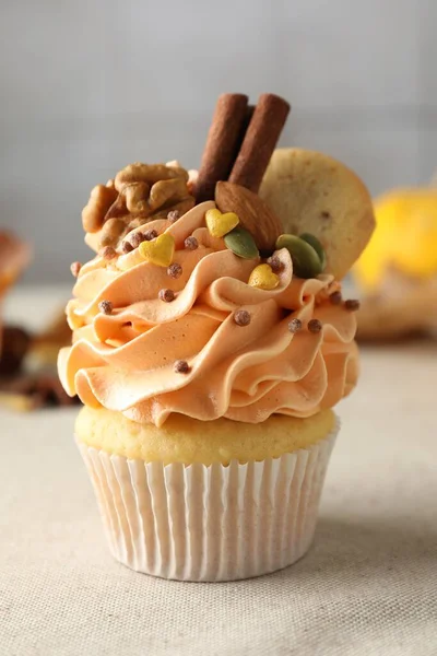 Delicious cupcake with color cream, spices, cookie and nuts on grey table, closeup