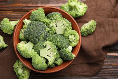 Fresh raw broccoli in bowl on table, flat lay