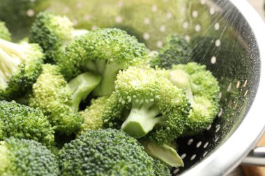 Fresh raw broccoli in colander on table, closeup
