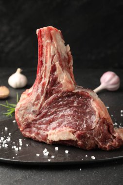 Bir parça çiğ et ve baharat siyah masada, yakın plan.