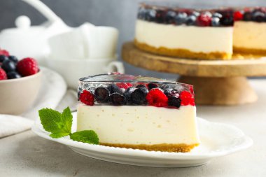 Piece of delicious cheesecake with berries and mint on light grey table, closeup