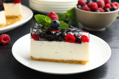 Lezzetli peynirli kek, böğürtlenli ve nane şekerli, siyah ahşap masa, yakın plan.