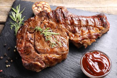 Ahşap masada baharat ve ketçaplı nefis ızgara biftek, yakın plan.