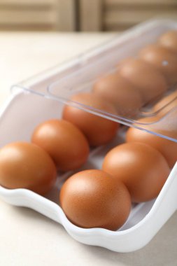 Beyaz masadaki kabın içinde çiğ tavuk yumurtası, yakın plan.