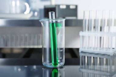 Laboratuvardaki yeşil sıvıyla cam deney tüpü ve test tüpü, yakın plan.