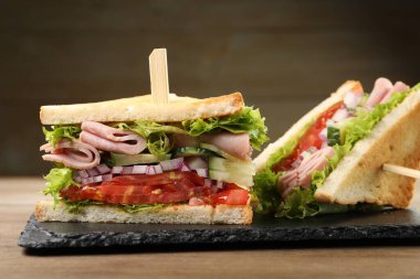 Tasty sandwiches with ham and vegetables on wooden table, closeup