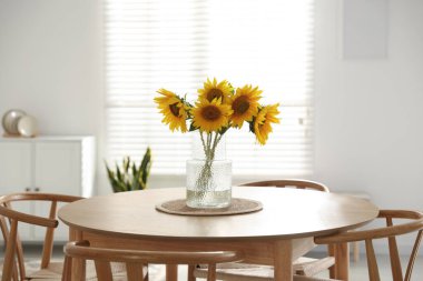 Beautiful sunflowers in vase on dining table at home