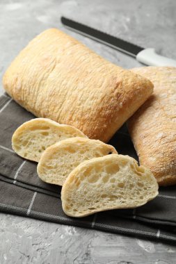 Gri desenli masada taze ciabatalar ve bıçak, yakın plan.