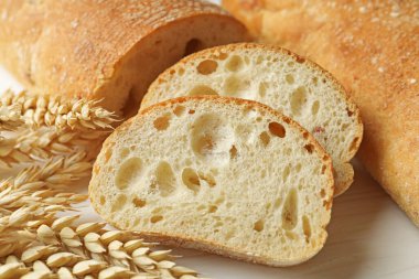 Taze çıtır ciabatalar ve beyaz ahşap masada buğday kulakları, yakın plan.