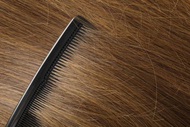 Comb with beautiful brown hair, closeup view