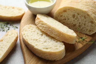 Taze ciabatta, bitkiler ve yağ gri masada, yakın plan.