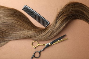 Açık kahverengi zemin üzerinde güzel saç, tarak ve makas kilidi, üst görünüm