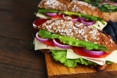 Peynirli ve sebzeli lezzetli ciabatta sandviçleri ahşap masada, yakın plan.