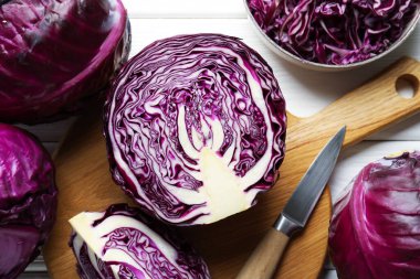 Taze kırmızı lahanalar ve beyaz ahşap masa üzerinde bıçak, düz yatıyordu.