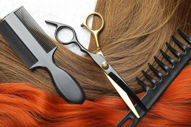 Farklı renklerde güzel saç telleri ve açık arkaplanda kuaför aletleri, düz yatış