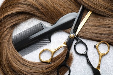 Beautiful hair strand and hairdresser's tools on light background, flat lay