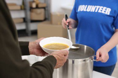 Yaşlılar için insani yardım. Gönüllü içeride kıdemli adama yemek veriyor, yakın plan.