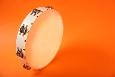 Tambourine on orange background. Space for text