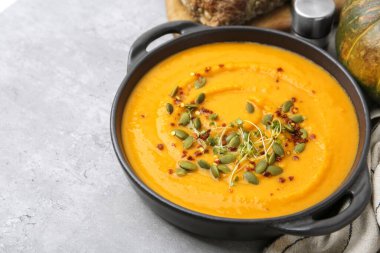 Delicious pumpkin soup served on grey table, closeup. Space for text
