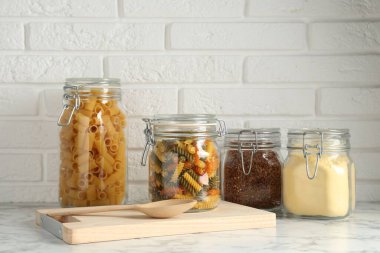 Beyaz mermer masanın üzerinde farklı ürünler olan cam kavanozlar