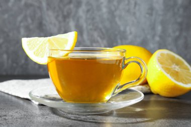 Aromatic tea in cup with lemons on grey table, closeup