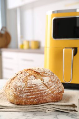 Mutfaktaki beyaz mermer masada taze pişmiş ekmek ve hava kızartma makinesi, yakın plan.