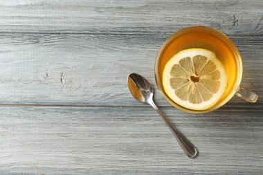 Aromatic tea with lemon in cup and spoon on wooden table, flat lay. Space for text