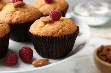 Fresh muffins with raspberries and almonds on table, closeup