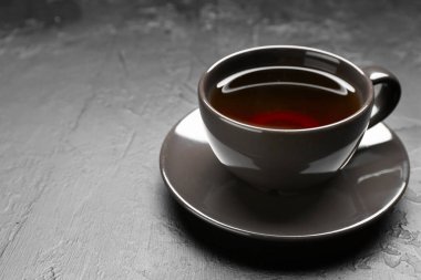 Aromatic tea in cup on black table, closeup. Space for text