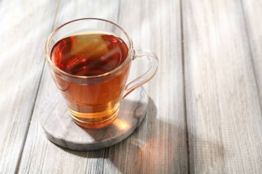 Aromatic black tea in glass cup on wooden table, closeup. Space for text