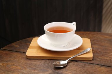 Aromatik siyah çay fincanda ve kaşık tahta masada, yakın plan.