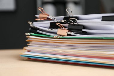 Many folders with documents and binder clips on wooden desk, closeup