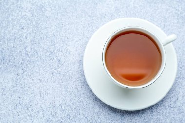 Açık gri masada fincanda koyu siyah çay, üst manzara. Metin için boşluk