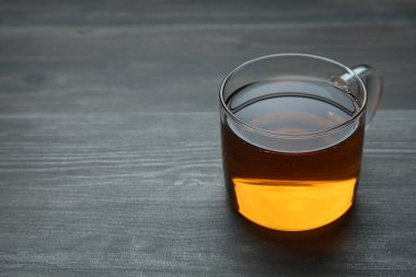 Aromatic black tea in glass cup on wooden table, closeup. Space for text