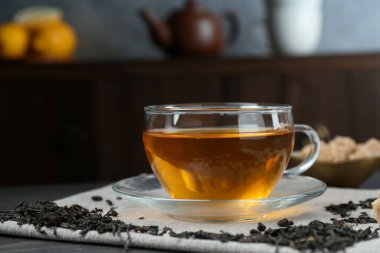 Aromatic black tea in glass cup, dried leaves and brown sugar on table, closeup. Space for text
