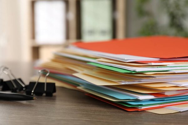 Множество папок с документами и скоросшивателями на деревянном столе.