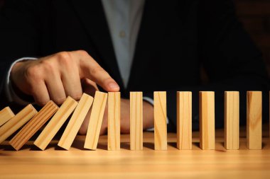 Risk. Tahta masada domino efektini durduran adam, yakın plan.