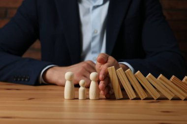 Risk. Tahta masada insan figürlerini domino etkisinden koruyan adam, yakın plan.