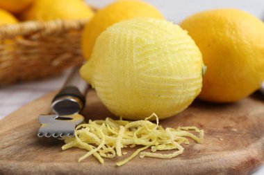 Lemon zest, fresh fruits and zester tool on table, closeup