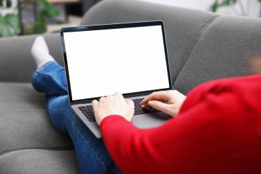 İçerideki kanepede dizüstü bilgisayarla çalışan bir kadın, yakın plan. Tasarım için model