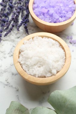 Sea salt, lavender and eucalyptus leaves on white marble table, closeup