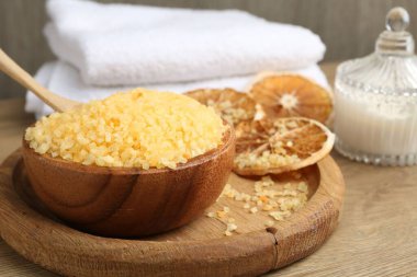 Doğal deniz tuzu, kurutulmuş portakal dilimleri ve ahşap masa üzerinde havlu, yakın plan.