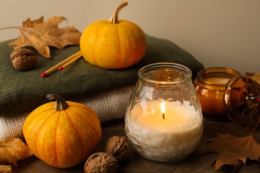 Ahşap masada yanan mumlar ve balkabaklarıyla sonbahar kompozisyonu, yakın plan