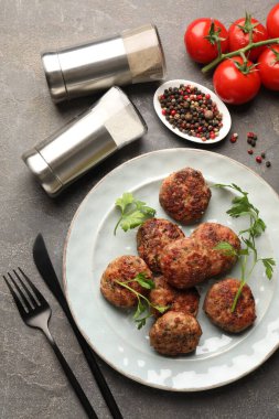 Tuz ve biberlikler, gri masada köfteler, düz konum