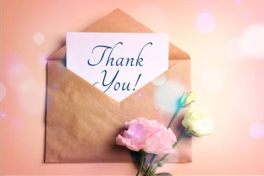 Zarfta teşekkür kartı ve pembe bej arka planda çiçekler, üst manzara. Bokeh ışıkları